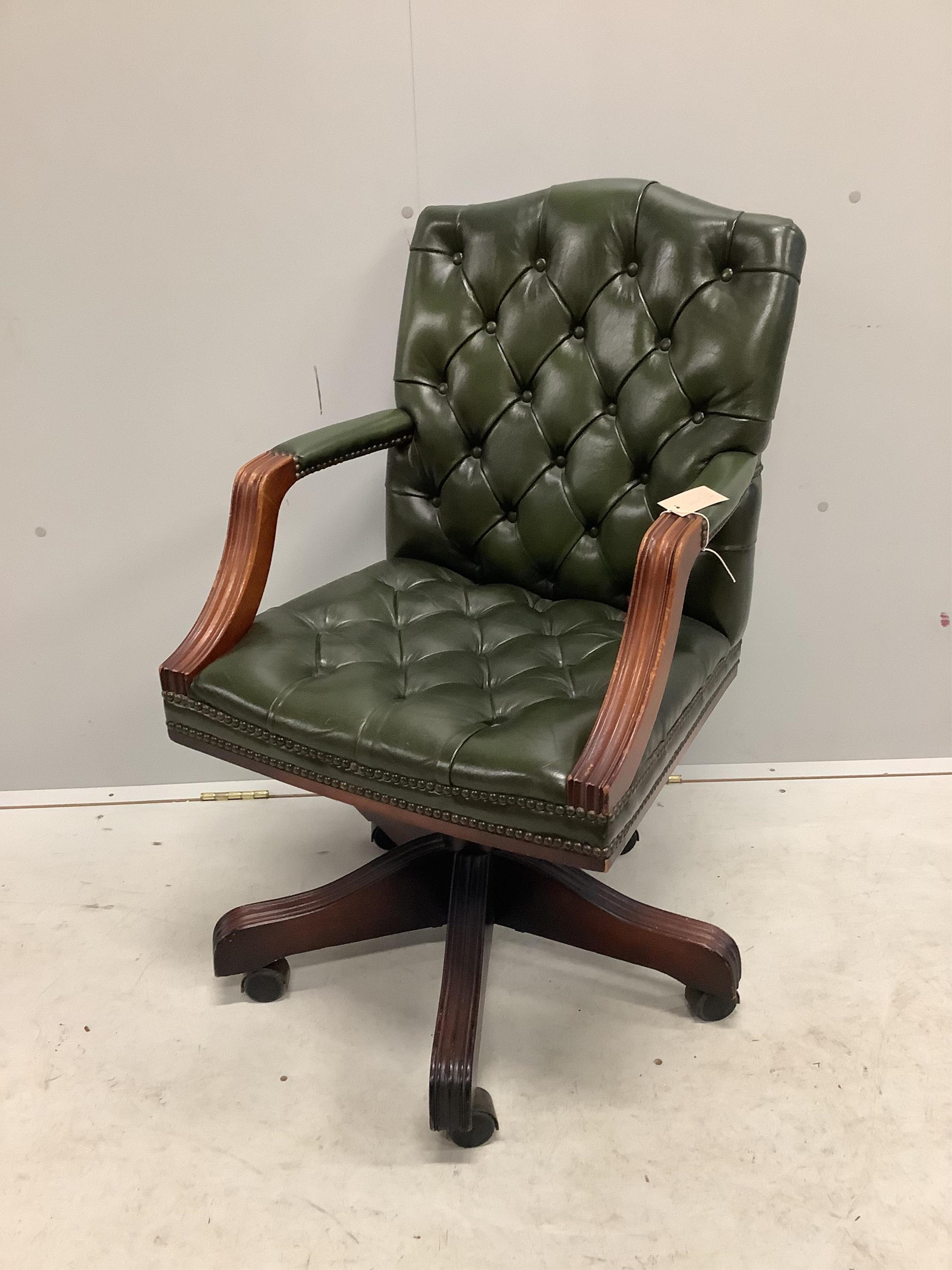 A reproduction mahogany and buttoned green leather swivel desk chair, width 56cm, depth 50cm, height 92cm. Condition - fair